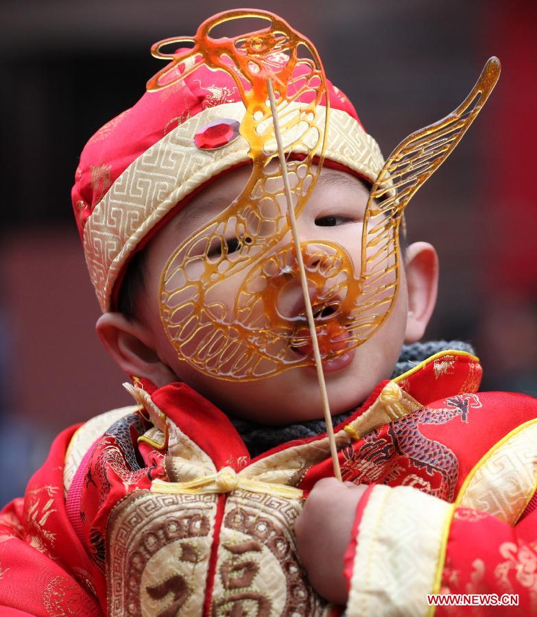 A child tastes a sugar figurine at a temple fair in Nanjing, capital of east China's Jiangsu Province, Feb. 11, 2013. Temple fair, a Chinese cultural gathering traditionally adjacent to temples, is usually held around the time of the Chinese Lunar New Year. At the fair, activities include worshiping deities, entertainment and shopping. (Xinhua/Li Wenbao)