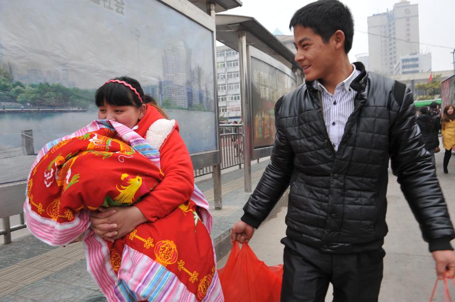 A couple bring their child and presents to visit the wife's family in Hefei, capital of east China's Anhui Province, Feb. 11, 2013. It is the second day of this year's Lunar New Year, or Spring Festival, on Feb. 11, when Chinese married women usually follow a tradition to visit parents with their husbands. (Xinhua/Yang Xiaoyuan) 