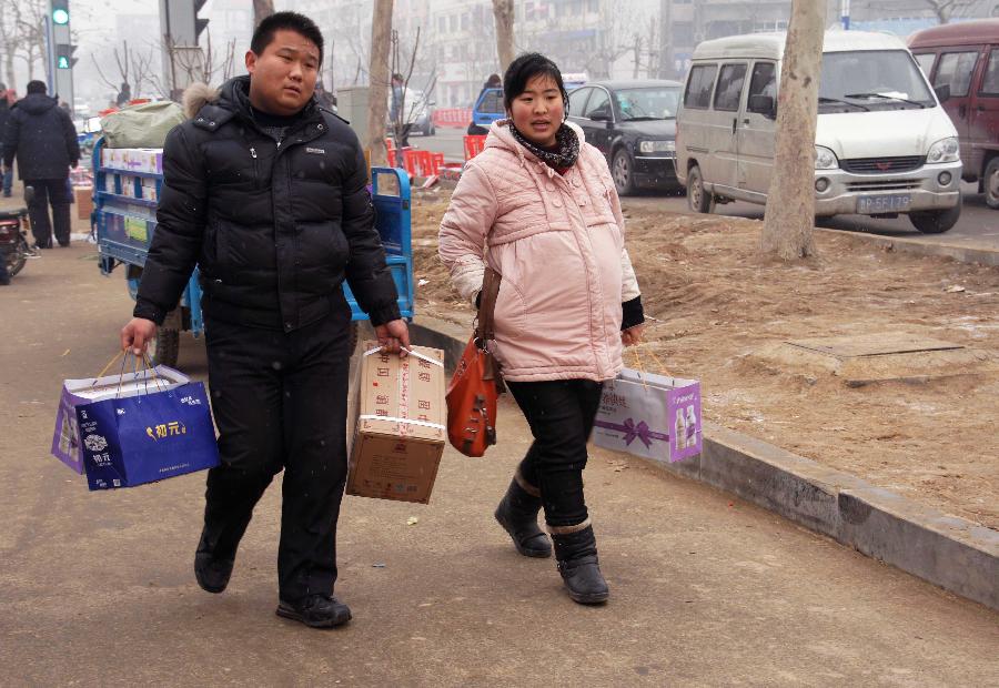 A pregnant woman and her husband bring presents to visit the wife's family in Liaocheng City, east China's Shandong Province, Feb. 11, 2013. It is the second day of this year's Lunar New Year, or Spring Festival, on Feb. 11, when Chinese married women usually follow a tradition to visit parents with their husbands. (Xinhua/Zhang Xianju) 