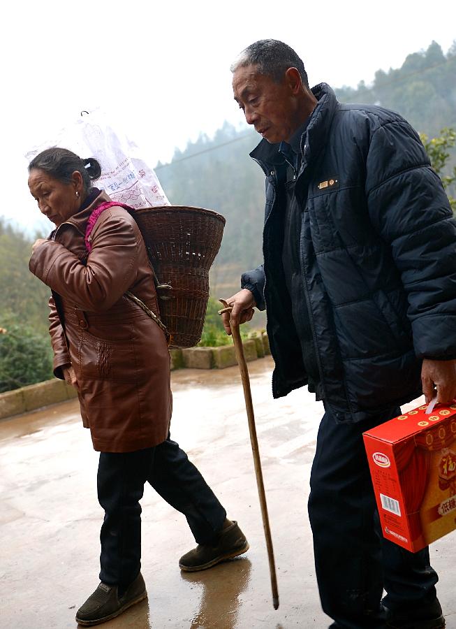 Shang Chunxiang shoulders presents to visit her parents with her 63-year-old husband Zhuo Guangjie in Xuan'en County of Enshi City, central China's Hubei Province, Feb. 11, 2013. It is the second day of this year's Lunar New Year, or Spring Festival, on Feb. 11, when Chinese married women usually follow a tradition to visit parents with their husbands. (Xinhua/Song Wen) 
