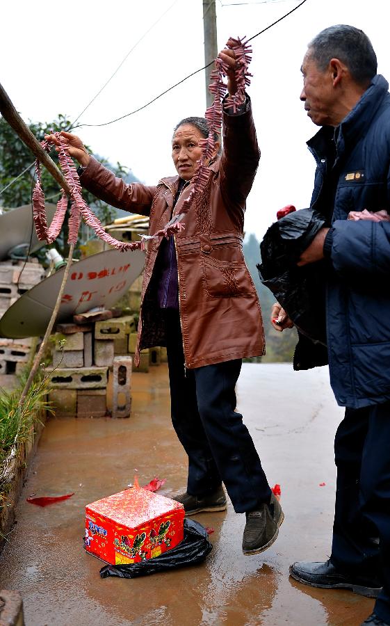 Zhuo Guangjie (R), 63, follows a local tradition to set off firebcrackers before entering the home of his father-in-law with his wife Shang Chunxiang in Xuan'en County of Enshi City, central China's Hubei Province, Feb. 11, 2013. It is the second day of this year's Lunar New Year, or Spring Festival, on Feb. 11, when Chinese married women usually follow a tradition to visit parents with their husbands. (Xinhua/Song Wen) 