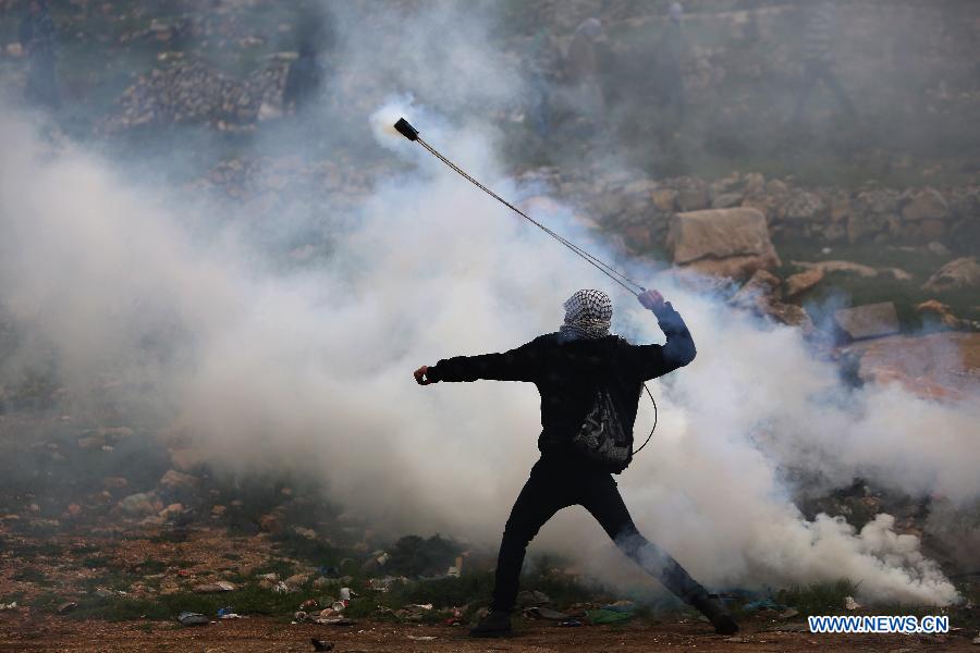 A Palestinian protestor throws stones towards Israeli troops outside Ofer Prison near the West Bank city of Ramallah on Feb.12, 2013. Five protestors supporting Palestinian prisoners were reported injured during the clashes. (Xinhua/Fadi Arouri) 