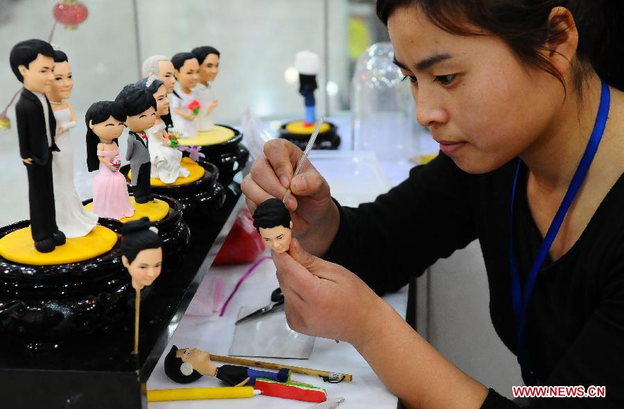 Dou Fengling, a folk artist, makes dough figurines of a couple in Liaocheng City, east China's Shandong Province, Feb. 12, 2013. The figurines, as miniatures of couples in love, are popular these days as the Valentine's Day approaches. (Xinhua/Zhang Zhenxiang)
