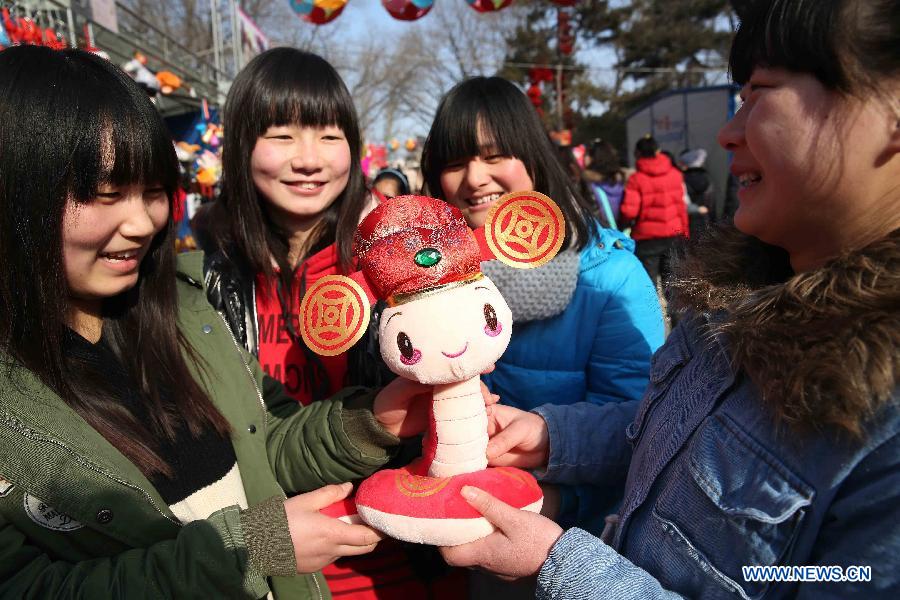 Visitors view a snake-shaped plush toy at a temple fair held to celebrate the Spring Festival, or the Chinese Lunar New Year, in Beijing, capital of China, Feb. 12, 2013. (Xinhua/Chen Xiaogen)