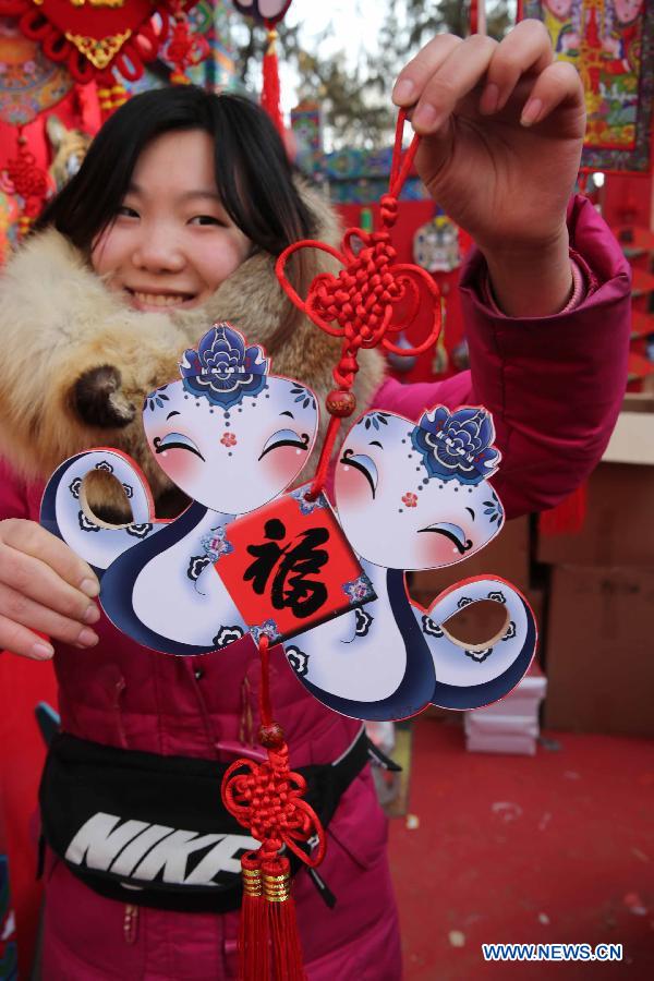 A visitor shows a snake-shaped ornament at a temple fair held to celebrate the Spring Festival, or the Chinese Lunar New Year, in Beijing, capital of China, Feb. 12, 2013. (Xinhua/Chen Xiaogen)