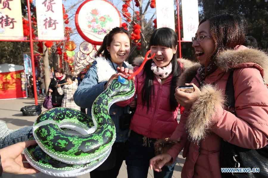 Visitors play with a snake-shaped inflatable toy at a temple fair held to celebrate the Spring Festival, or the Chinese Lunar New Year, in Beijing, capital of China, Feb. 12, 2013. (Xinhua/Chen Xiaogen)