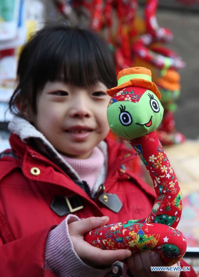 A young girl views a snake-shaped toy at a temple fair held to celebrate the Spring Festival, or the Chinese Lunar New Year, in Beijing, capital of China, Feb. 12, 2013. (Xinhua/Chen Xiaogen)