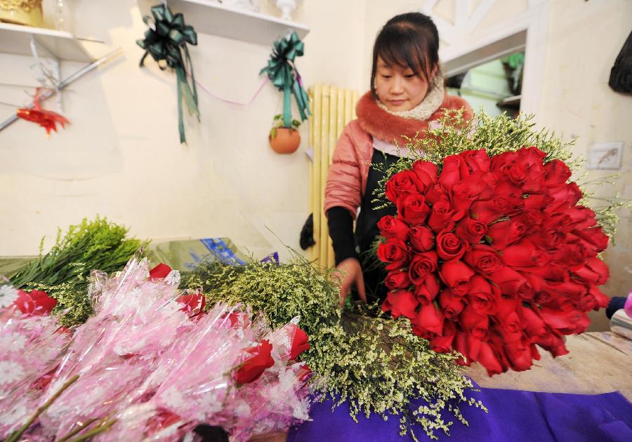 A woman works on a bunch of roses in a flower shop in Yinchuan, capital of northwest China's Ningxia Hui Autonomous Region, Feb. 13, 2013. Florists in Yinchuan began their preparation of bouquets for the upcoming Valentine's Day. (Xinhua/Peng Zhaozhi)