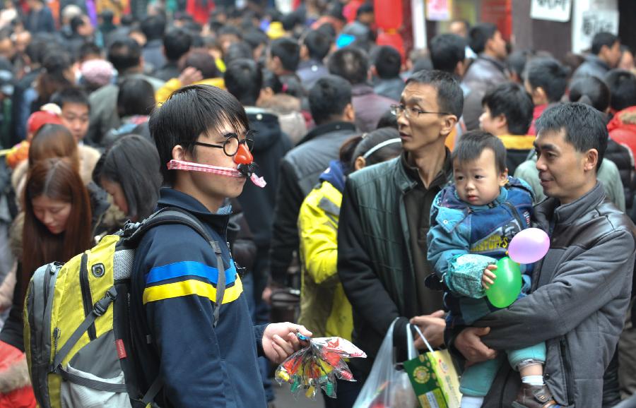 A vendor (L Front) sells toys on a street of the Ciqikou Town in southwest China's Chongqing Municipality, Feb. 13, 2013. Large amount of tourists visited the time-honored Ciqikou during the Spring Festival holiday. (Xinhua/Liu Chan) 