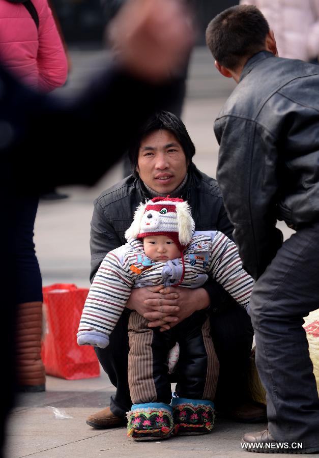 A man holds a child at Zhengzhou Railway Station in Zhengzhou, capital of central China's Henan Province, Feb. 15, 2013. China's railways will be tested Friday, when passenger flows peak at the end of the Spring Festival holiday. Some 7.41 million trips will be made on the country's railways with travelers returning to work as the week-long Lunar New Year celebration draws to a close, the Ministry of Railways said. (Xinhua/Zhao Peng) 