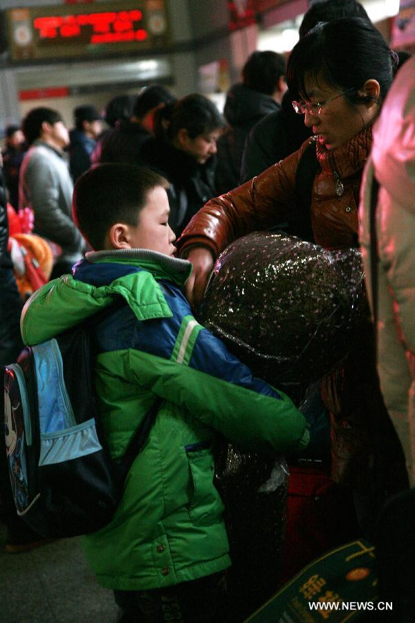 A young boy carries a bag for his parent in the waiting room of Nantong Coach Station in Nantong, east China's Jiangsu Province, Feb. 15, 2013. Many children travel with their families during the Spring Festival travel rush. The Spring Festival holiday came to an end on Friday. (Xinhua/Cui Genyuan) 