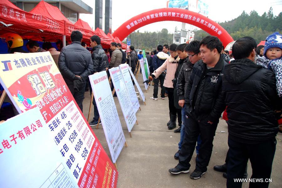 People watch job requirements at an industrial park in Wuyuan, east China's Jiangxi Province, Feb. 15, 2013. As the Spring Festival holiday draws to a close, various job hunting fairs are held among cities across the country. (Xinhua/Wang Guohong)