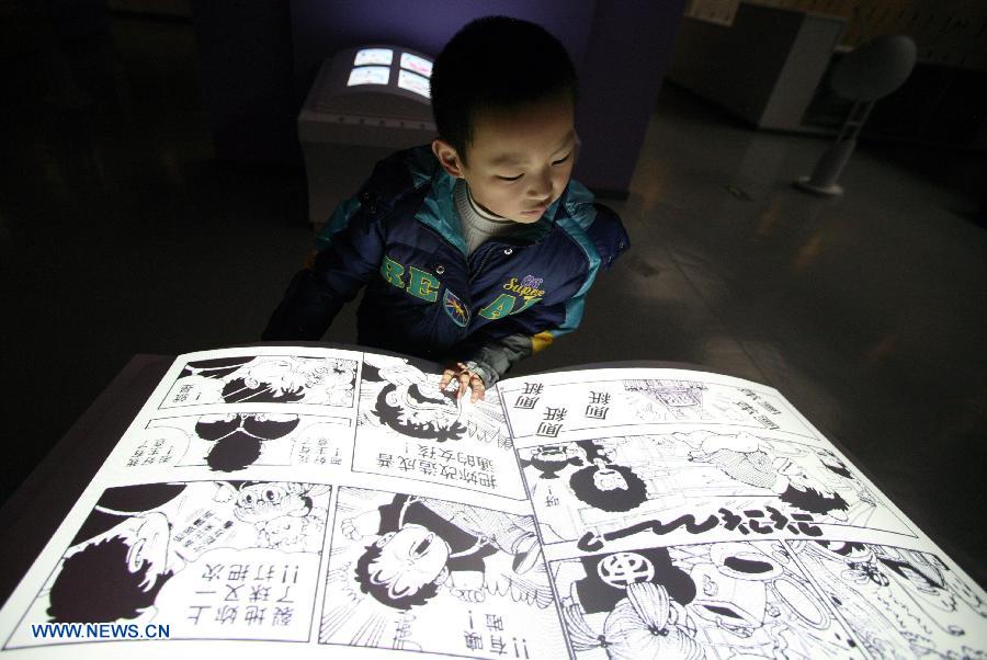 A child reads an electric cartoon book at a cartoon experience center in Nanjing Science and Technology Museum in Nanjing, capital of east China's Jiangsu Province, Feb. 14, 2013. A cartoon experience center covering an area of 2700 square meters started its test operation on Thursday, offering a place for fans to know about the cartoon culture and industry. (Xinhua) 