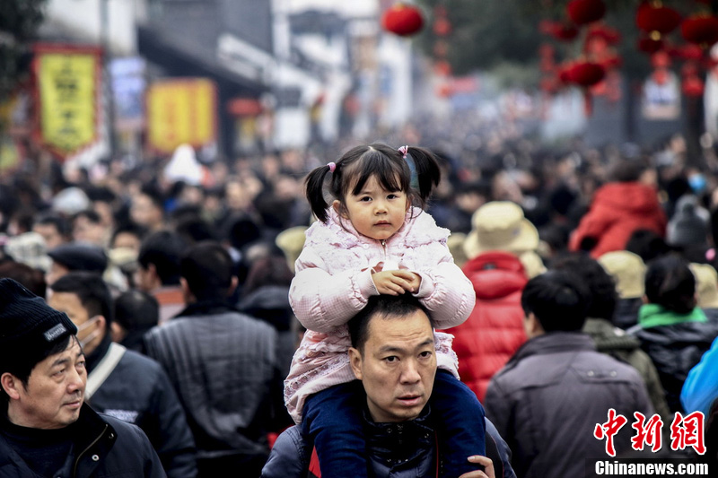 A girl sitting on shoulders is seen among hundreds of thousands of tourists flooding an ancient town in Shaoxing, Zhejiang province, Feb. 13, 2013. (Chinanews.com/Li Ruichang)