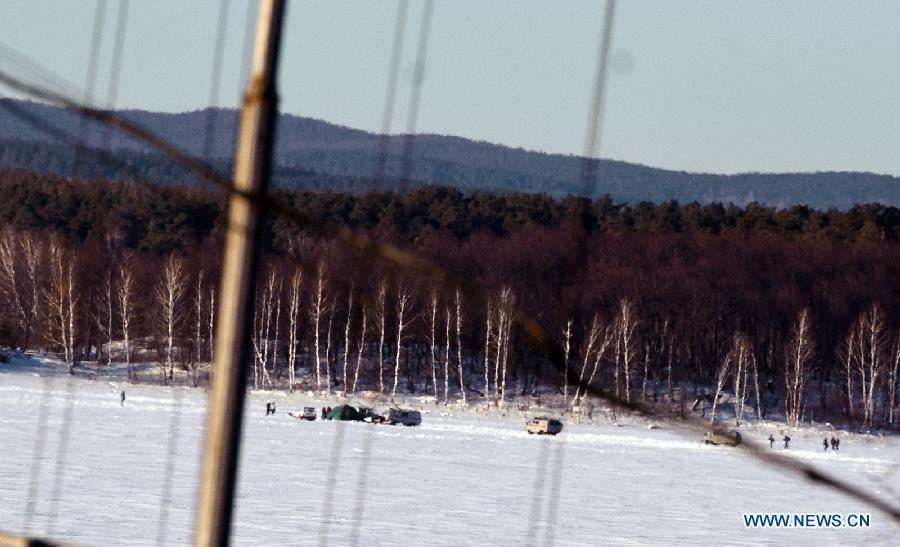 Russian police and members of Russian ministry of emergency situations gather around the site of the meteorite fall at the chebarkul lake near Chelyabinsk, about 1500 kilometers east of Moscow, Russia, Feb. 16, 2013. A meteorite burst into the sky over Russia's Urals region on Friday. Emergency Situations Minister Vladimir Puchkov said there was no proof that meteoritic fragments have been found. (Xinhua/Jiang Kehong) 