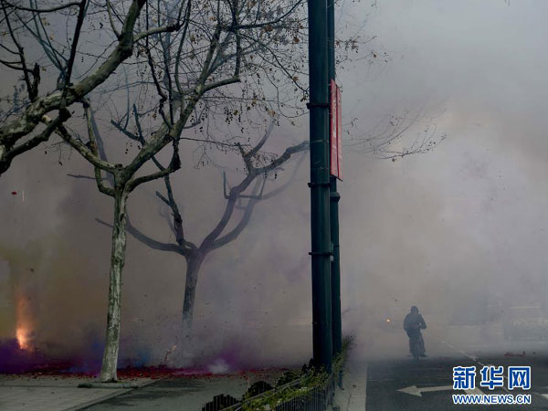 Smog generated by the explosion of fireworks permeates a street in Hangzhou, eastern China's Zhejiang province, Saturday morning, February 16, 2013. Firework sprees are staged in many places around China on Saturday morning, the first workday after this year's Spring Festival holidays. Many Chinese businessmen pray this way for a properous new year, but such activities have also been blamed for burdening cleaning workers and worsening air pullution. （Photo/Xinhua) 