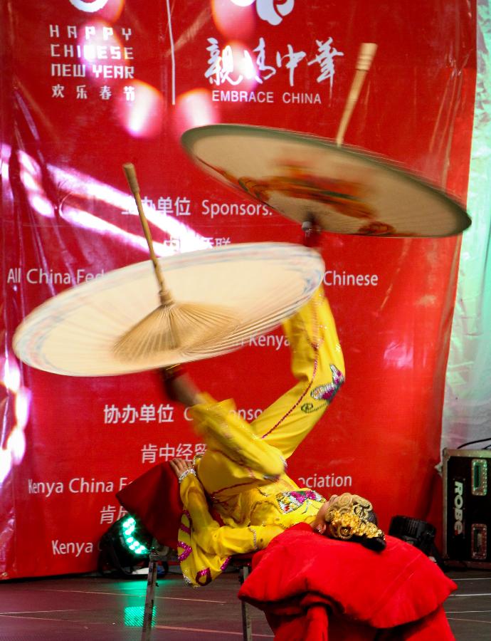 Actress Jin Linlin performs "kicking umbrella" during the performances of the Embrace China Art Group of the All-China Federation of Returned Overseas Chinese in Nairobi, Kenya, Feb. 16, 2013. (Xinhua/Meng Chenguang) 