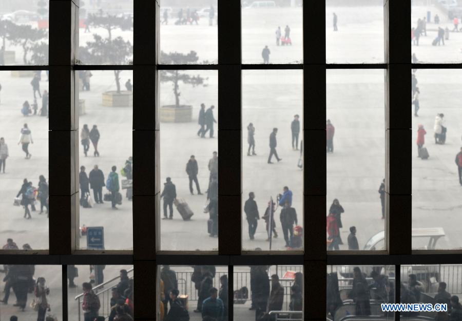 Passengers are seen through a giant window in the railway station in Shijiazhuang, capital of north China's Hebei Province, Feb. 17, 2013. China saw a travel rush after the week-long Spring Festival holiday as millions of workers move to big cities for better working opportunities. (Xinhua/Zhu Xudong) 