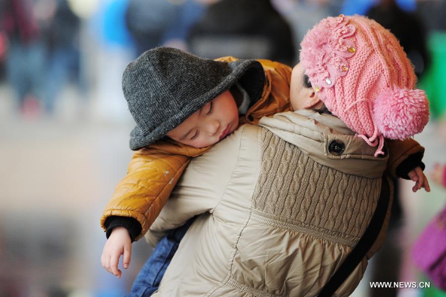 A child falls asleep in his mother's chest at the Guiyang Railway Station in Guiyang, capital of southwest China's Guizhou Province, Feb. 17, 2013. When the Spring Festival holiday comes to an end, migrant workers start to leave their hometowns in Guizhou for job opportunities in China's more affluent coastal provinces. Many have to take their children with them. (Xinhua/Liu Xu)