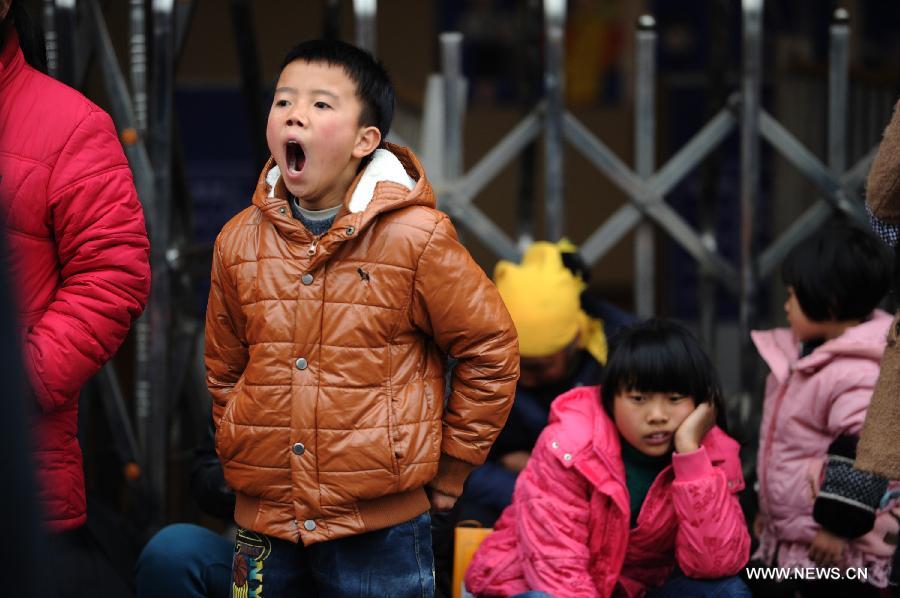 A boy yawns while waiting for the train at the Guiyang Railway Station in Guiyang, capital of southwest China's Guizhou Province, Feb. 17, 2013. When the Spring Festival holiday comes to an end, migrant workers start to leave their hometowns in Guizhou for job opportunities in China's more affluent coastal provinces. Many have to take their children with them. (Xinhua/Liu Xu)