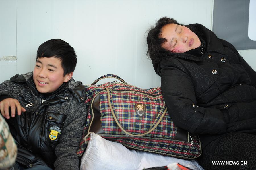 A boy and his mother wait for the train at the Guiyang Railway Station in Guiyang, capital of southwest China's Guizhou Province, Feb. 17, 2013. When the Spring Festival holiday comes to an end, migrant workers start to leave their hometowns in Guizhou for job opportunities in China's more affluent coastal provinces. Many have to take their children with them. (Xinhua/Liu Xu)