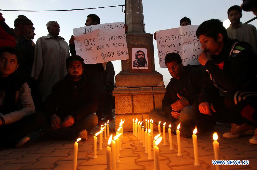 Students hold placards near the photograph of 2001 Indian parliament attack convict Mohammed Afzal Guru during a candle light protest demanding Guru's body back in Srinagar, summer capital of Indian-controlled Kashmir, Feb. 17, 2013. (Xinhua/Javed Dar)