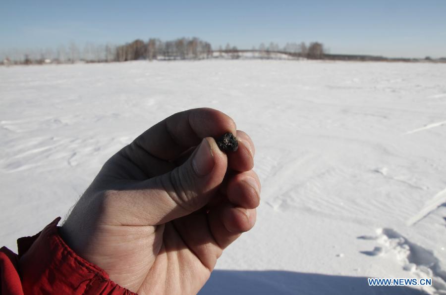 Photo taken on Feb. 17, 2013 released by RIA Novosti agency shows a scientific researcher holding a meteor fragments found in the chebarkul lake region near Chelyabinsk, about 1,500 kilometers east of Moscow, Russia. Scientists have found fragments of a meteor that exploded over Russia's central Urals and triggered a shock wave that injured hundreds and shattered scores of windows, experts said Monday. (Xinhua/RIA Novosti)  