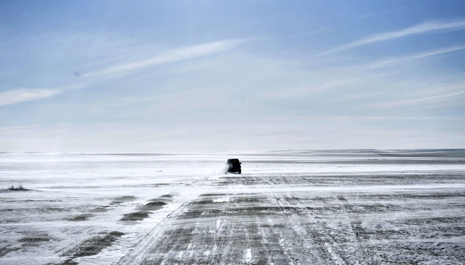 A photo taken on Feb. 14 shows a vehicle running on the snow-covered road in XiIin GoI Prairie of Inner Mongolia autonomous region. The prairie turned into a white world because of thick snow lasting from October to next year's April, which provided an ideal environment for snow sports and tourist activities. (Xinhua/Zhao Tingting)
