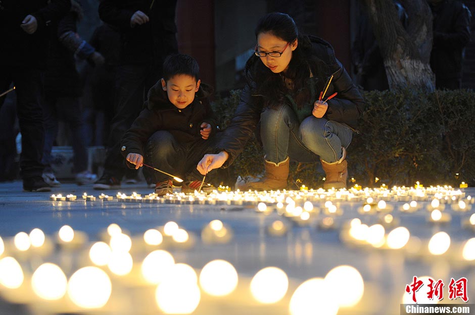 A mother and her son light oil lamps at the Guangren Lama Temple in Xi'an, Shaanxi Province, February 17, 2013. Many people went to the temple to pray for good fortune on Sunday. (CNS/Zhang Yuan)