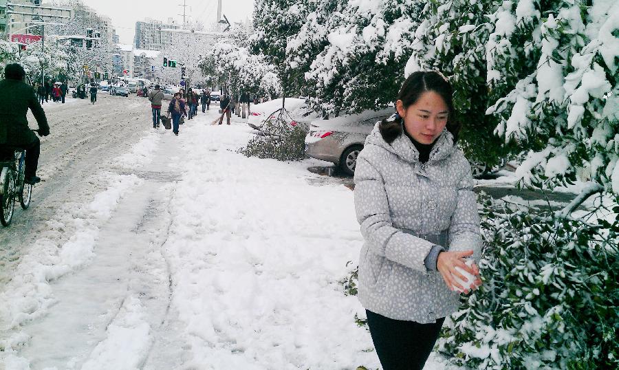 A citizen makes a snowball on a snowy road in Nanjing, capital of east China's Jiangsu Province, Feb. 19, 2013. A snowstorm hit Jiangsu province on Feb. 19 morning and local meteorological bureau has issued a blue alert for the snowfall. (Xinhua/Shen Peng) 