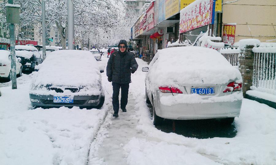  A citizen walks on a snowy road in Nanjing, capital of east China's Jiangsu Province, Feb. 19, 2013. A snowstorm hit Jiangsu province on Feb. 19 morning and local meteorological bureau has issued a blue alert for the snowfall. (Xinhua/Shen Peng) 