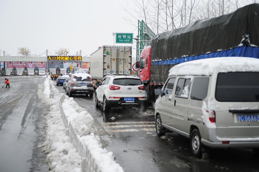 Vehicles wait at the entrance of an intercity express way which has been closed due to heavy snowfall in Hefei, capital of east China's Anhui Province, Feb. 19, 2013. Snowstorm hit multiple places in Anhui Tuesday morning, disturbing the local traffic. (Xinhua/Du Yu) 