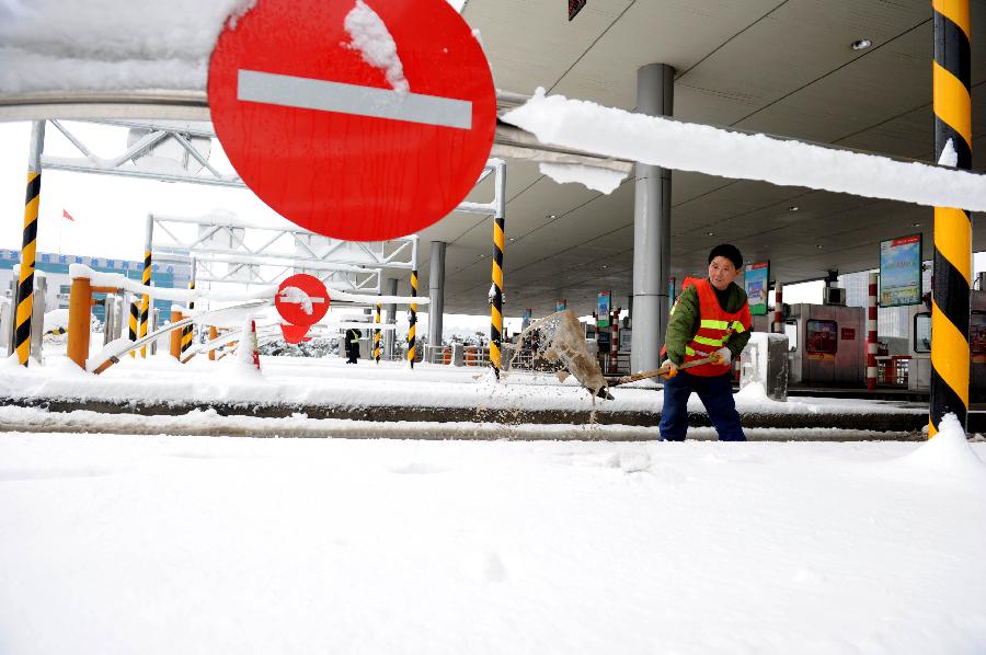 A staff member cleans the snow at an entrance of an intercity express way in Hefei, capital of east China's Anhui Province, Feb. 19, 2013. Snowstorm hit multiple places in Anhui Tuesday morning, disturbing the local traffic. (Xinhua/Liu Junxi) 