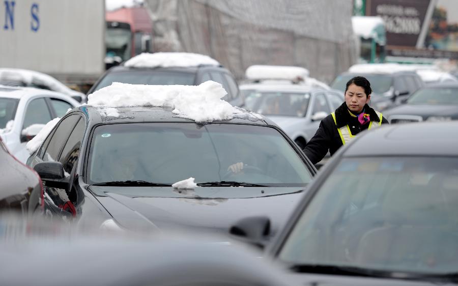 A staff member directs the vehicles at an entrance of an intercity express way which has been closed due to heavy snowfall in Hefei, capital of east China's Anhui Province, Feb. 19, 2013. Snowstorm hit multiple places in Anhui Tuesday morning, disturbing the local traffic. (Xinhua/Liu Junxi) 