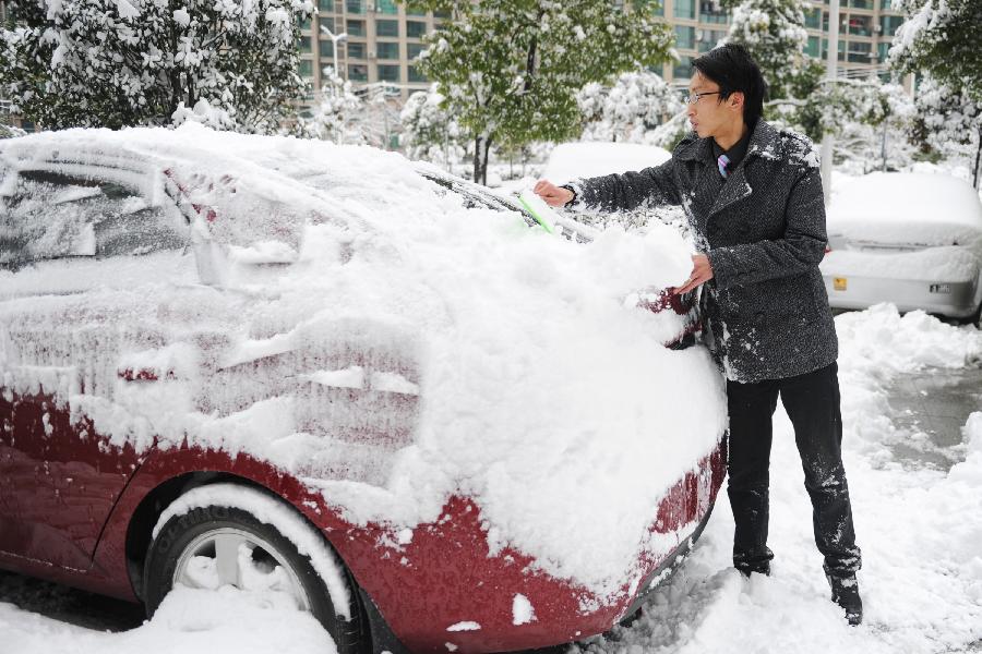 A man cleans the snow on his car in Hefei, capital of east China's Anhui Province, Feb. 19, 2013. Snowstorm hit multiple places in Anhui Tuesday morning, disturbing the local traffic. (Xinhua/Du Yu) 