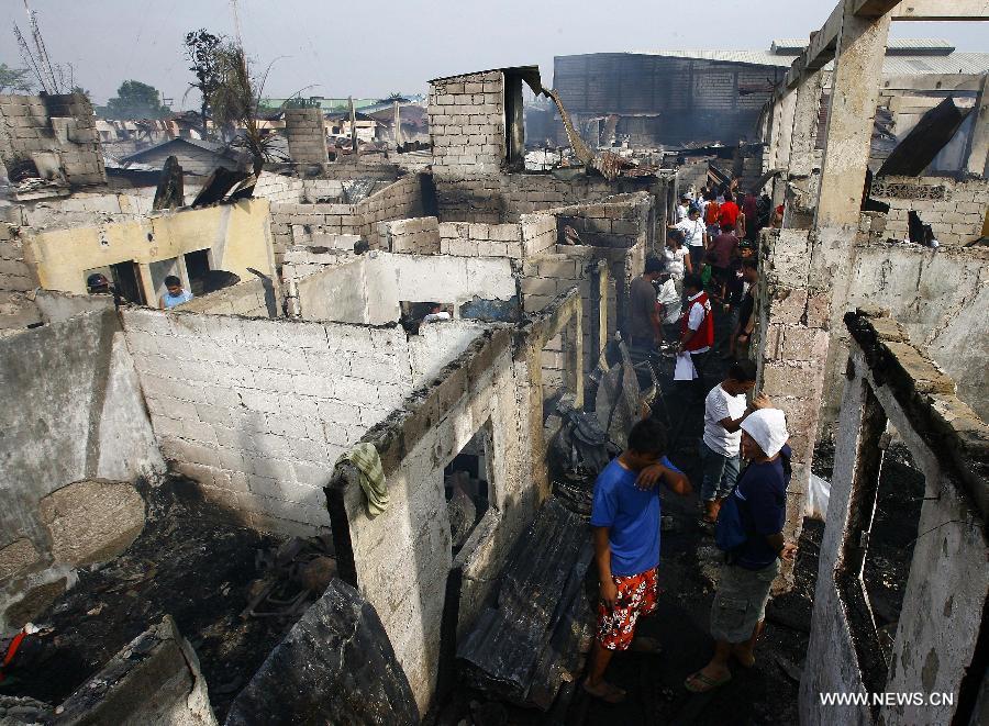 Residents look for reuseable materials at their charred homes after a fire hit a residential area in Valenzuela City, the Philippines, Feb. 19, 2013. Around 500 houses were razed in the fire, leaving 2,000 residents homeless. (Xinhua/Rouelle Umali) 