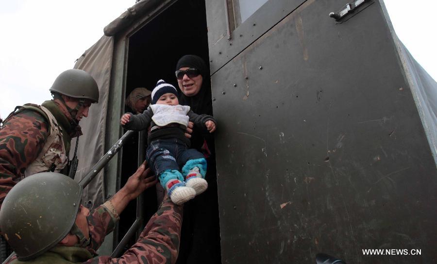 A Jordanian soldier helps Syrian refugees after they crossed the border from Syria into Jordan near Mafraq, Feb. 18, 2013. According to the Jordanian Armed Forces sources, around 89,000 Syrian refugees fleeing from the violence in their country have crossed the Jordanian border since the beginning of 2013. (Xinhua/Mohammad Abu Ghosh)  