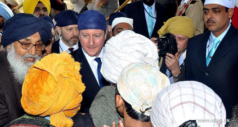 British Prime Minister David Cameron (C) is greeted by locals during his visit in Amritsar, India, Feb. 20, 2013. British Prime Minister David Cameron Wednesday paid homage to the victims of the 1919 killing of civilians by British troops in northwest Indian city of Amritsar. (Xinhua/Stringer) 