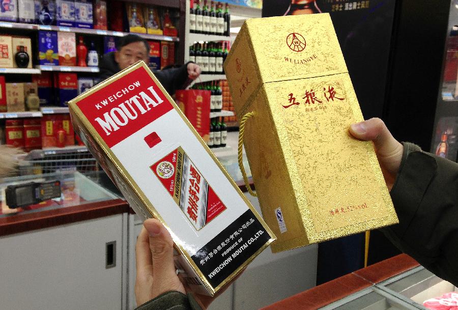 A man holds Kweichow Moutai Liquor and Wuliangye Liquor at a supermarket in Beijing, capital of China, Feb. 19, 2013. Two Chinese liquor makers, Kweichow Moutai Co. Ltd and Wuliangye Yibin Co. Ltd, have been fined 449 million yuan, equivalent to 1 percent of all sales of the two companies throughout 2012, for their involvement in price monopoly activity. (Xinhua/Li Xin) 