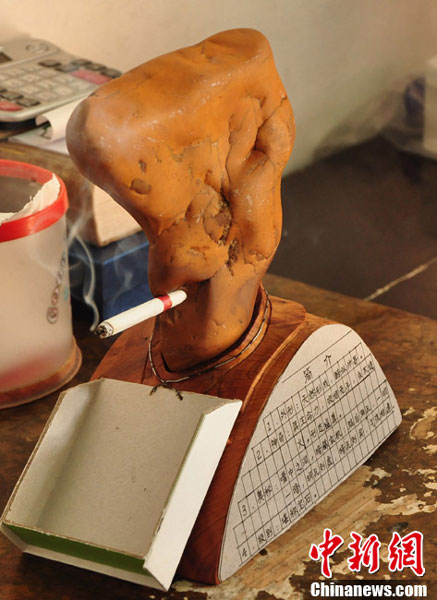 An undated photo shows a red-color rock is fitted with an instructional plaque and a handy ashtray. The rock can smoke a cigarette in under five minutes, according to Luo Yuanshui, the rock collector owner. Luo from Longyan in southeast China's Fujian province said that he found it on a mountain.(Chinanews.com)