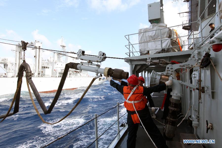 Crew members onboard missIle destroyer Harbin adjust the fuel pipe from the supply ship Weishanhu at South China Sea, Feb. 20, 2013. The supply ship Weishanhu reinforced the missile destroyer Harbin and the frigate Mianyang on Wednesday with fuel, fresh water and other materials. The 14th naval squad, sent by the Chinese People's Liberation Army (PLA) Navy, departed Saturday from China to the Gulf of Aden and Somali waters for escort missions. The fleet comprises three ships -- the missile destroyer Harbin, the frigate Mianyang and the supply ship Weishanhu -- carrying two helicopters and a 730-strong troop. (Xinhua/Rao Rao)