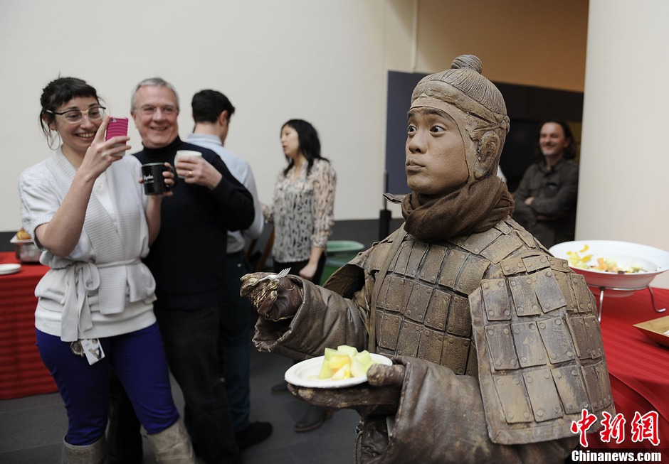 Visitors take pictures of a “live” Terra Cotta Warrior eating fruits. The art performer dressed in Terracotta Warriors attracts the attention of many visitors. It is the first time for Chinese cultural relics on the theme of Qin Dynasty to be displayed in the United States.（Photo Source: Chinanews.com/ Chen Gang）