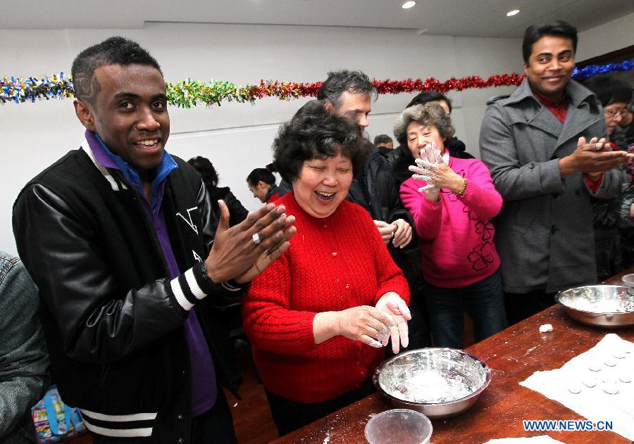 Ma Liang (1st L) from Madagascar learns to make the Yuanxiao, glutinous rice flour dumpling with sweetened stuffing, at a community in Shanghai, east China, Feb. 21, 2013. Some foreign students on Thursday came to a community in Shanghai to feel the atmosphere of the upcoming Lantern Festival. (Xinhua/Chen Fei) 