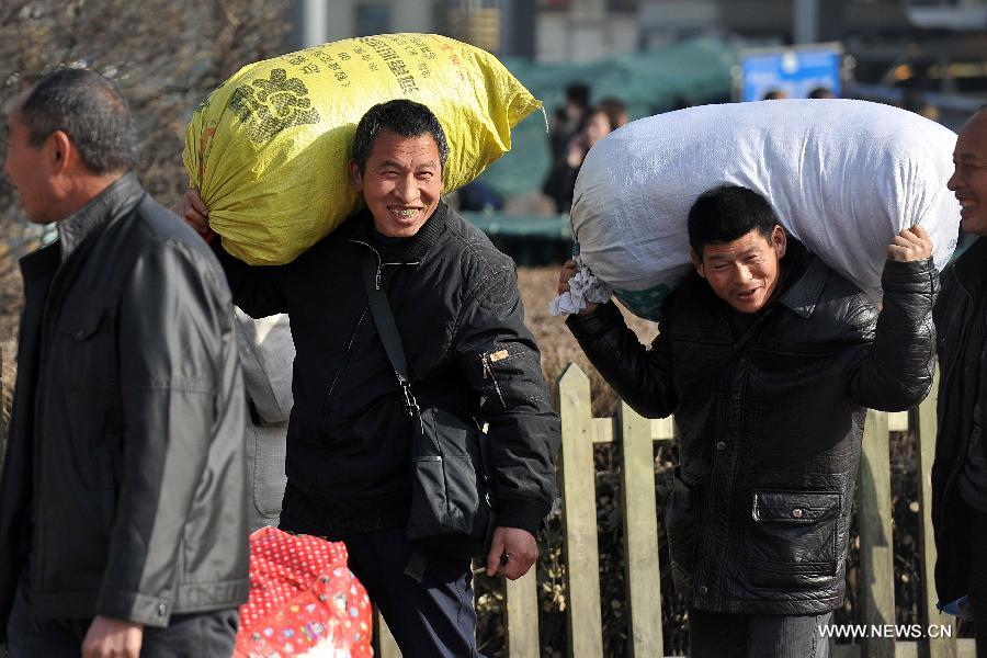 Passengers carry their bags on the square of the train station in Taiyuan, capital of north China's Shanxi Province, Feb. 21, 2013. Many people started their trips back to their working places after the Spring Festival holiday in recent days. (Xinhua/Zhan Yan) 