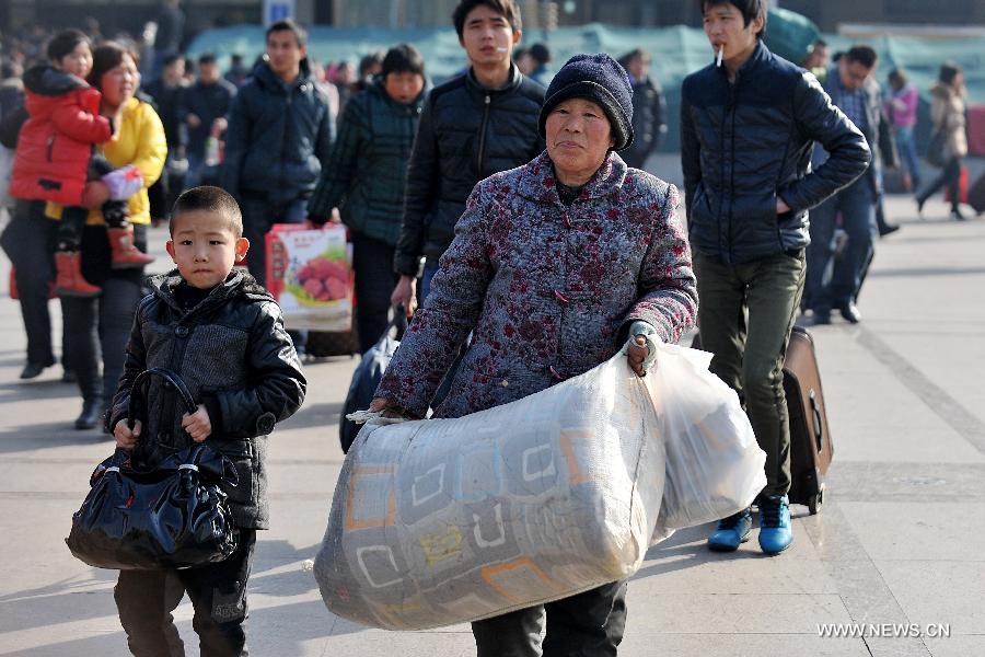 Passengers carry their bags on the square of the train station in Taiyuan, capital of north China's Shanxi Province, Feb. 21, 2013. Many people started their trips back to their working places after the Spring Festival holiday in recent days. (Xinhua/Zhan Yan) 