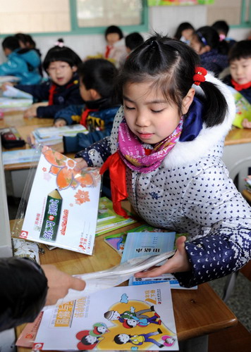 Students get new books in a primary school in Nanjing, Jiangsu province on Thursday, the first day of the new semester for around 800,000 students in the city's kindergartens, primary and secondary schools. The starting day, scheduled for Tuesday, was postponed due to a sudden snowfall that blanketed the province late on Monday night. (Photo/Xinhua) 