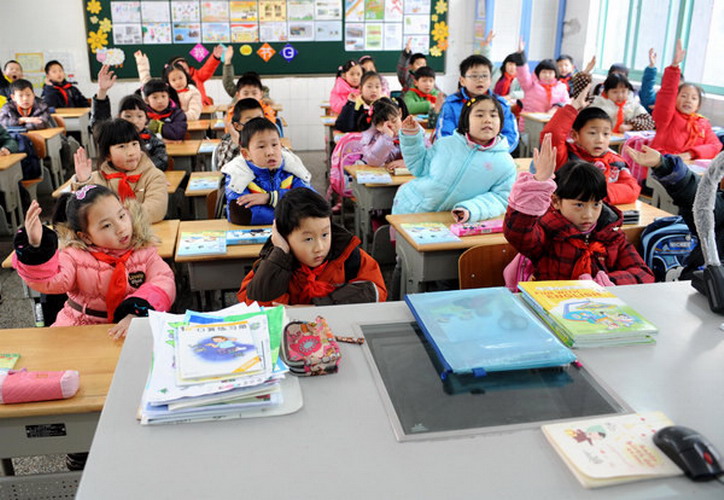 Students raise their hands to answer a teacher's question in a primary school in Nanjing, Jiangsu province, reads in class on Thursday, the first day of the new semester for around 800,000 students in the city's kindergartens, primary and secondary schools. The starting day, scheduled for Tuesday, was postponed due to a sudden snowfall that blanketed the province late on Monday night. (Photo/Xinhua)