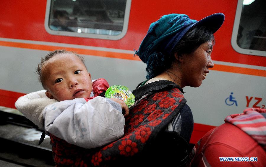 A passenger carries a child on her back at the railway station in Chengdu, capital of southwest China's Sichuan Province, Feb. 22, 2013. As the number of travellers rises before the Lantern Festival, many children went back with their parents back to the workplaces. (Xinhua/Xue Yubin)