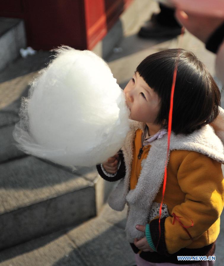 A child eats the cotton candy at an ancient street in north China's Tianjin Municipality, Feb. 23, 2013. As the Lantern Festival falls on the next day, various lanterns were set up at the ancient street, which offers a place for local citizens in Tianjin to experience the culture of the festival. (Xinhua/Zhang Chenlin)