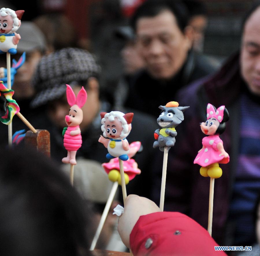 Visitors are attracted by toys made of dough at an ancient street in north China's Tianjin Municipality, Feb. 23, 2013. As the Lantern Festival falls on the next day, various lanterns were set up at the ancient street, which offers a place for local citizens in Tianjin to experience the culture of the festival. (Xinhua/Zhang Chenlin)
